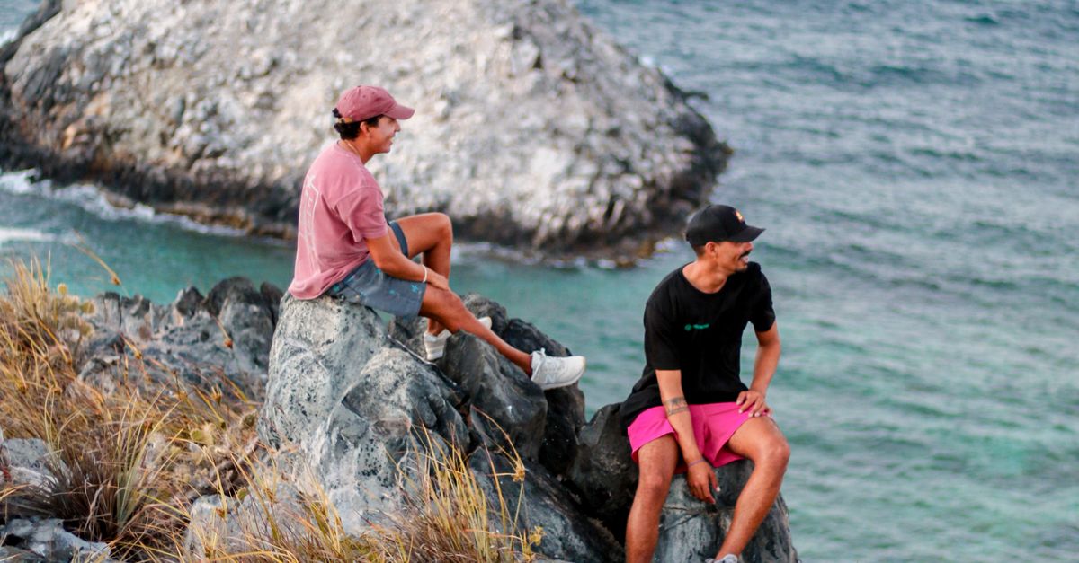 Resting On Rocks Woman and Man Resting on Rocks on Seashore · Free Stock Photo