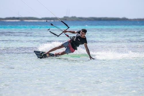 A Man Touching the Water while Kitesurfing