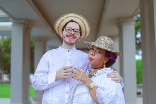 Free Couple in traditional clothing smiling and drinking cold beverages outdoors. Stock Photo
