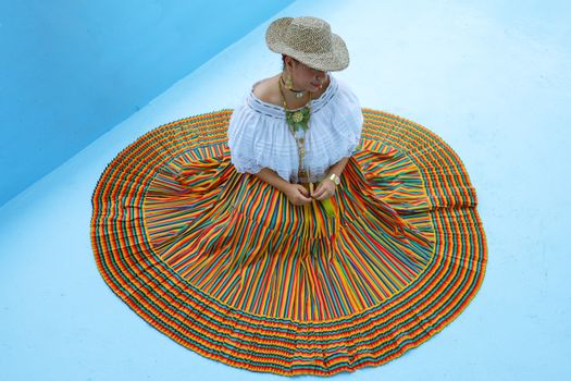 Woman Posing in a Striped Traditional Skirt and Straw Hat