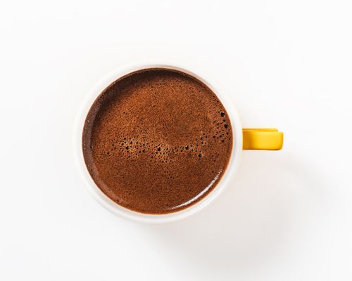 Free A close-up top view of a steaming cup of freshly brewed Turkish coffee in a white mug with a yellow handle. Stock Photo