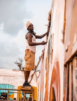 An artist paints a mural on a wall in Accra, Ghana, showcasing vibrant street art.