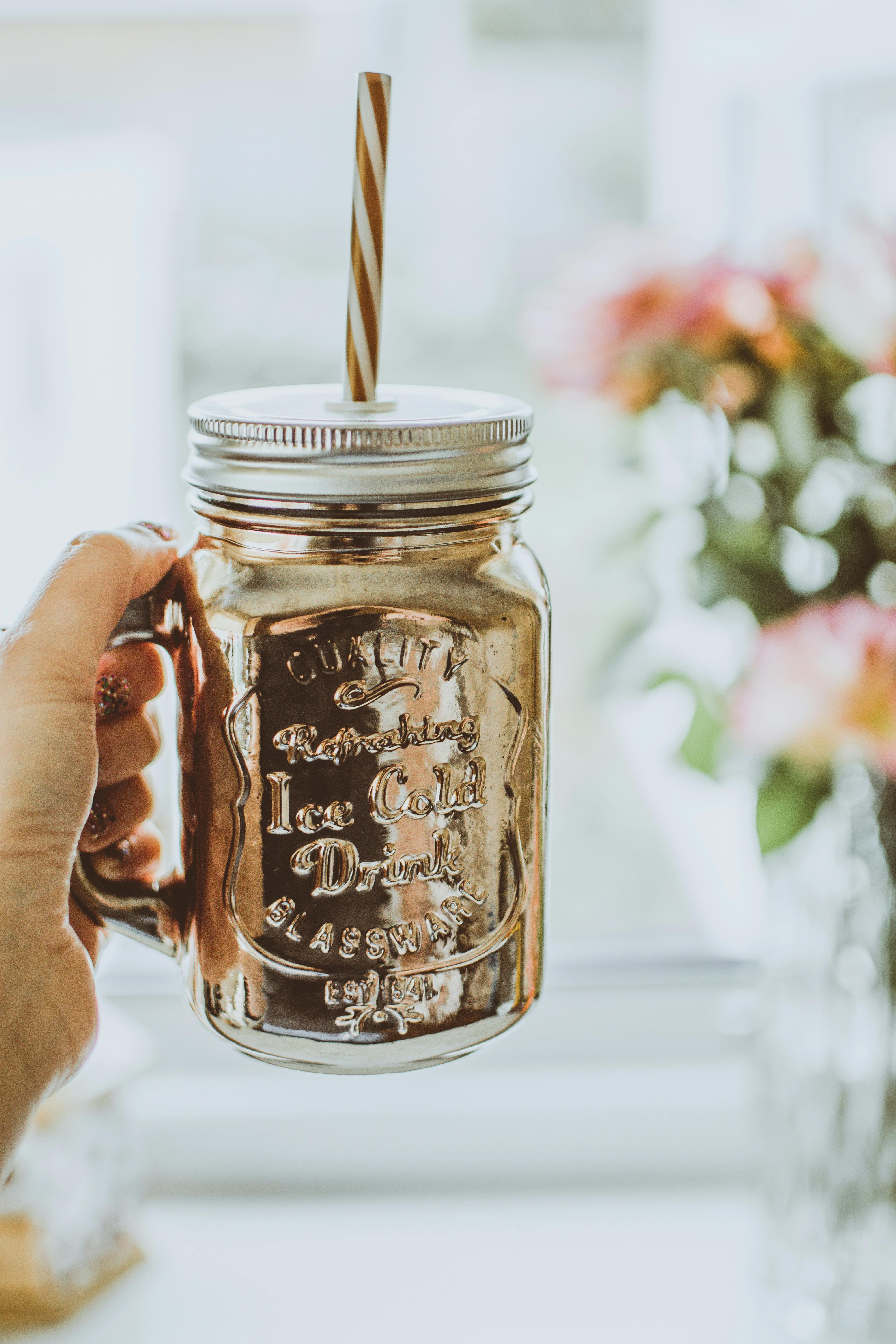 Brown Mason Jar Mug With Straw Beside Plant on Table · Free Stock Photo