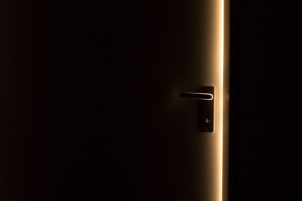 A pivot door standing ajar with warm light behind it