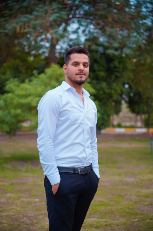 Free A confident man dressed in white stands outdoors, exuding style and poise. Stock Photo