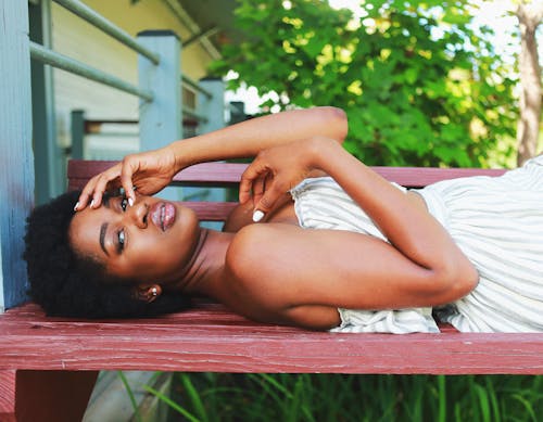 Photo Of Woman Laying On Wooden Bench 