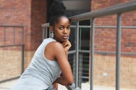 一位时尚的年轻女子靠在砖墙上，在户外拍照摆姿势