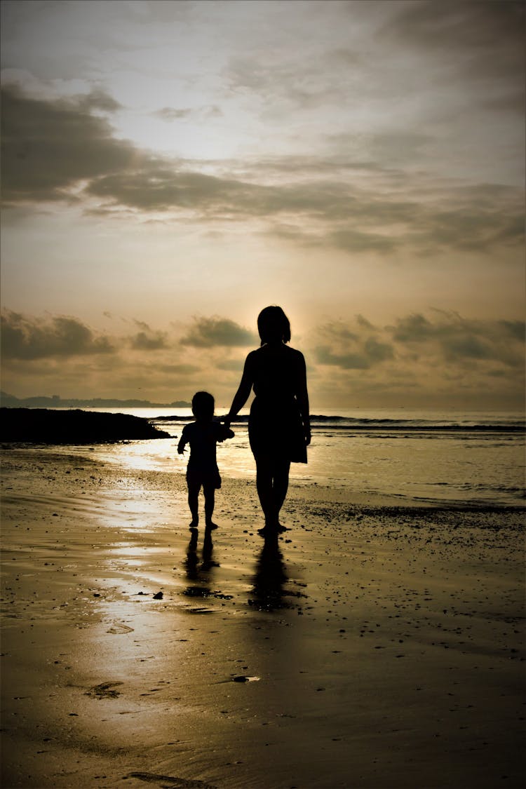 Silhouette Of Mother And Child Walking On Beach