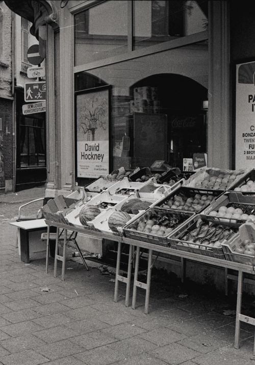 Free Black and white photo of an urban market stall displaying fresh produce on a city sidewalk. Stock Photo