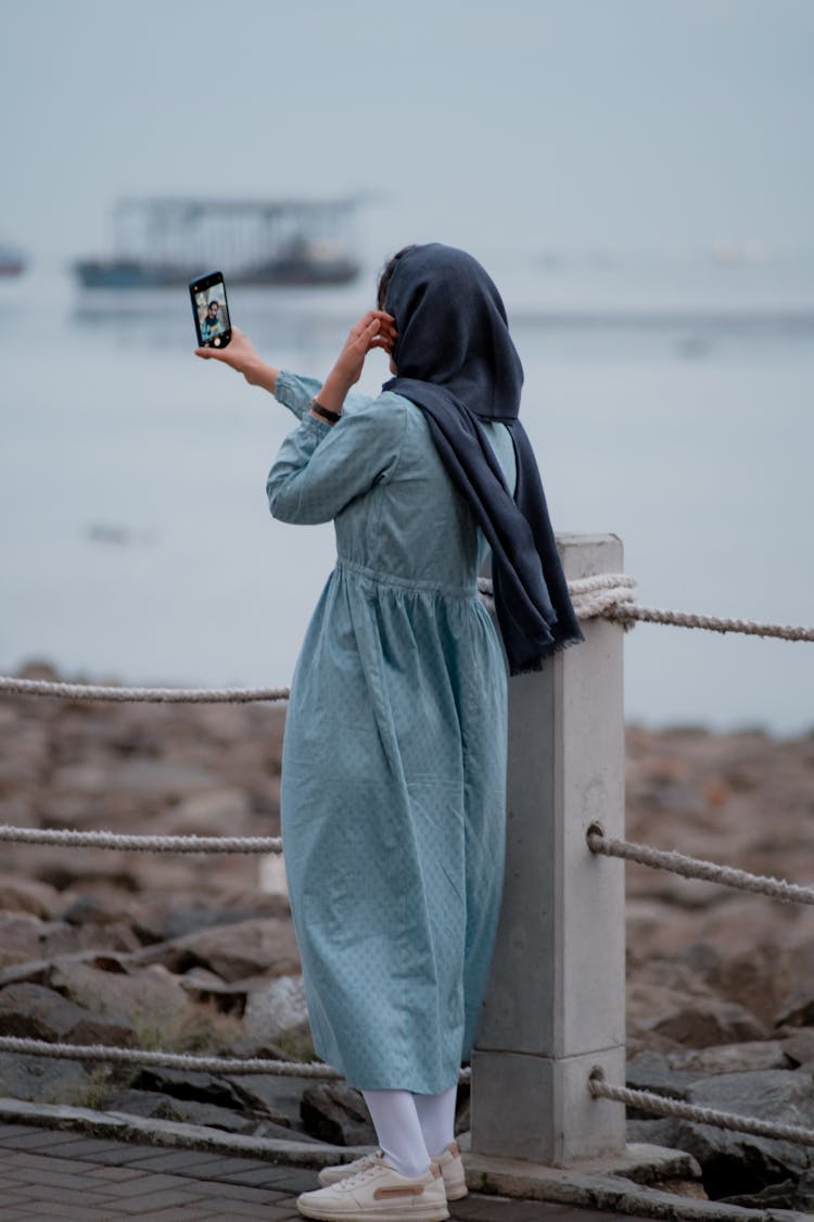 Woman Using A Smartphone Near A Body Of Water