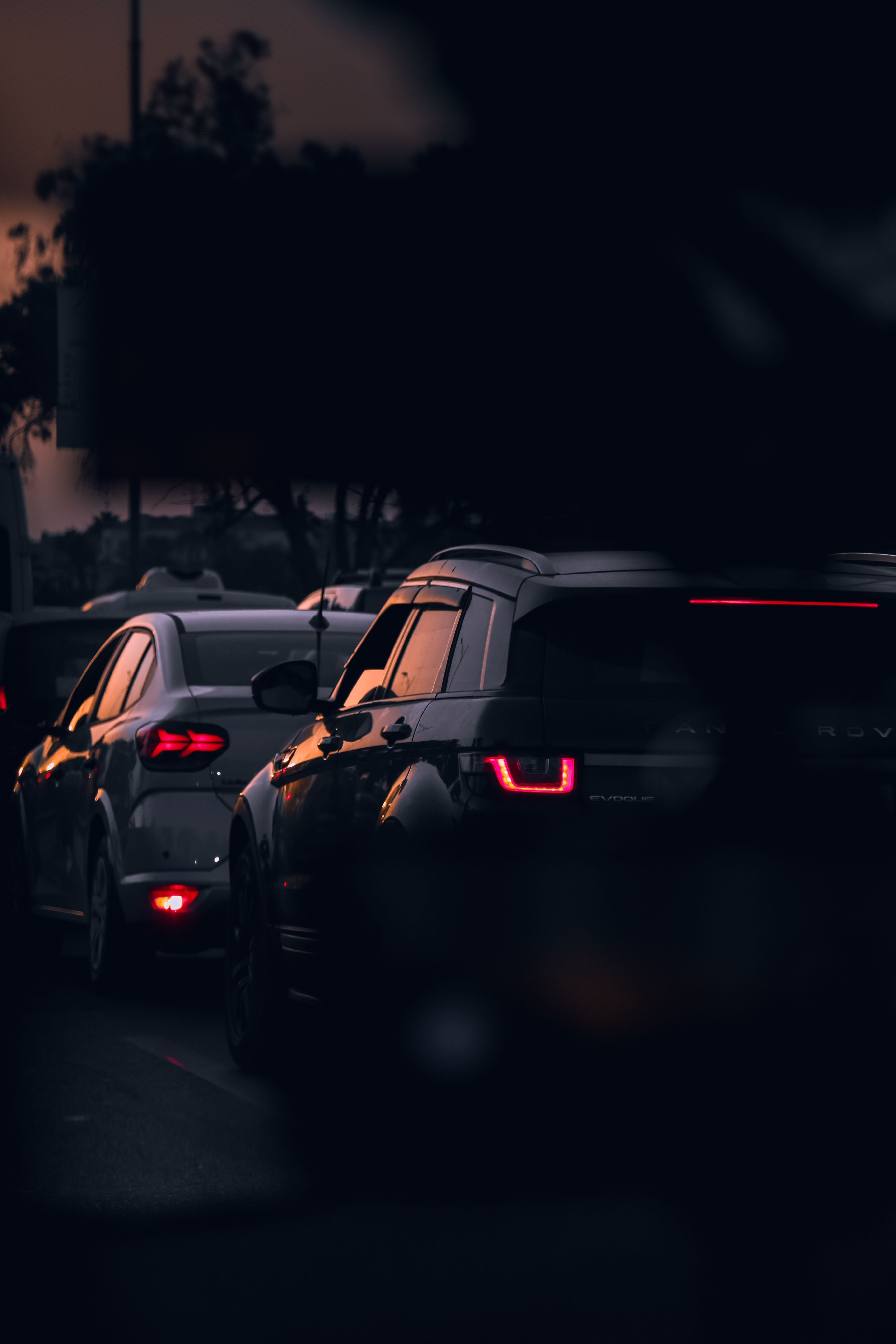 A moody city street scene with cars in traffic at dusk, highlighting vehicle headlights.