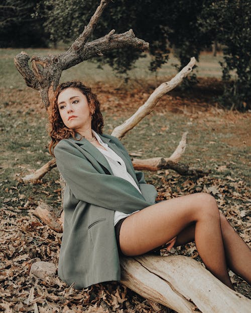 A Woman in Gray Coat Sitting on Wood Log