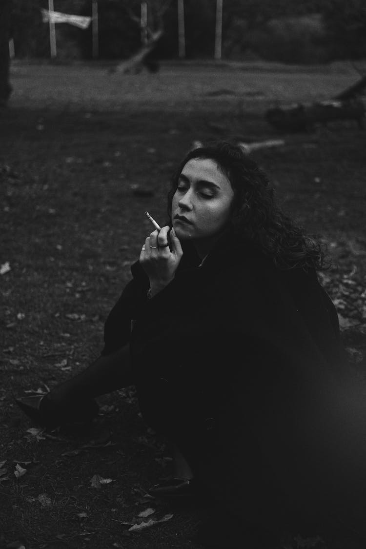 Woman Sitting On The Ground With A Cigarette 