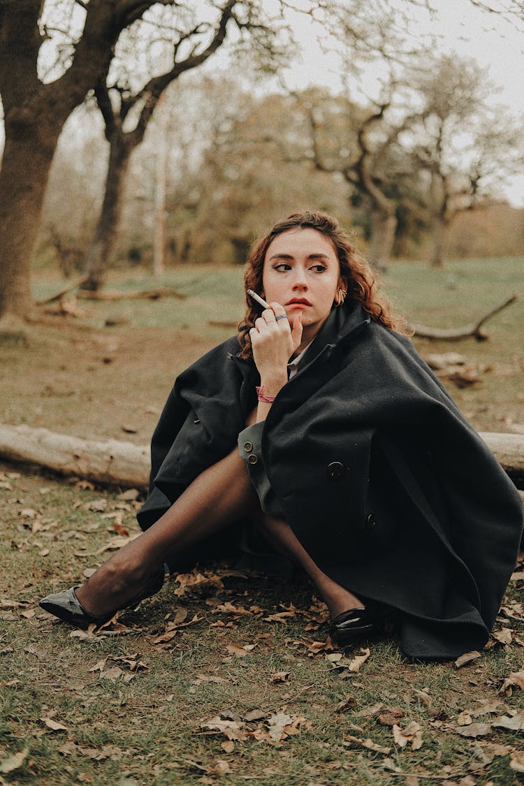 Woman Sitting On The Ground With A Cigarette 