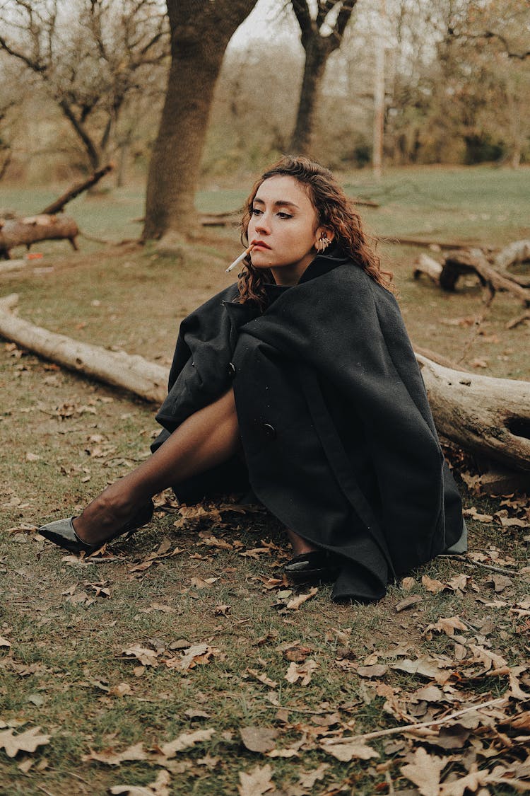 Woman Sitting On The Ground With A Cigarette 