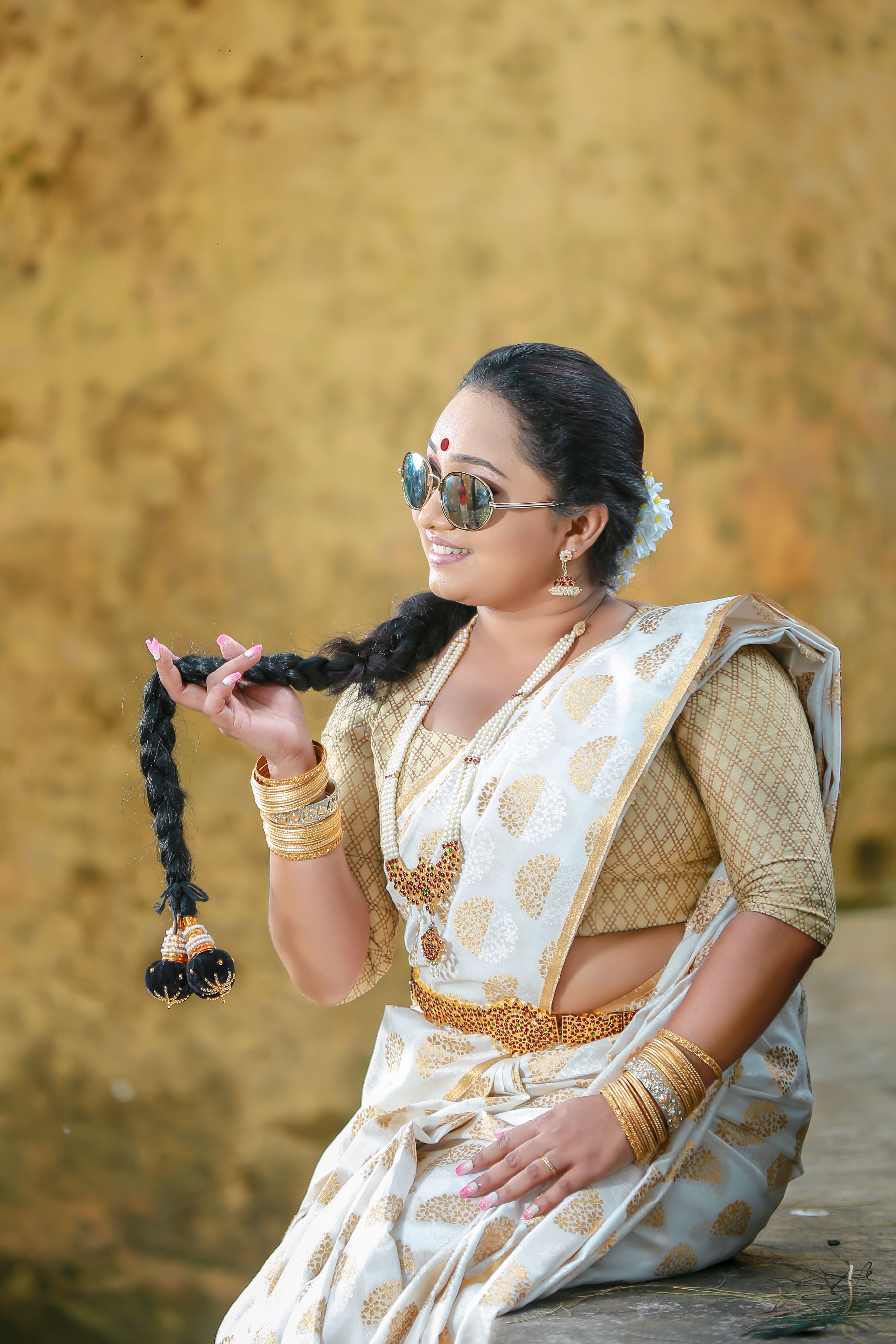 A stylish woman in a traditional sari with sunglasses, showcasing cultural fashion.