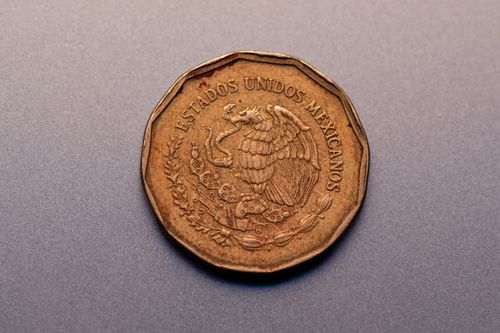 Free High-resolution close-up of a copper Mexican coin featuring national emblem on gray surface. Stock Photo