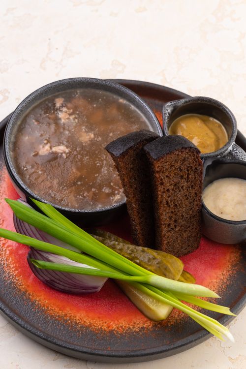 Free A delicious bowl of soup served with rye bread, onion, pickles, and sauces. Stock Photo