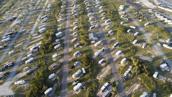 Aerial view of a grassy campsite filled with caravans and motorhomes on pitches