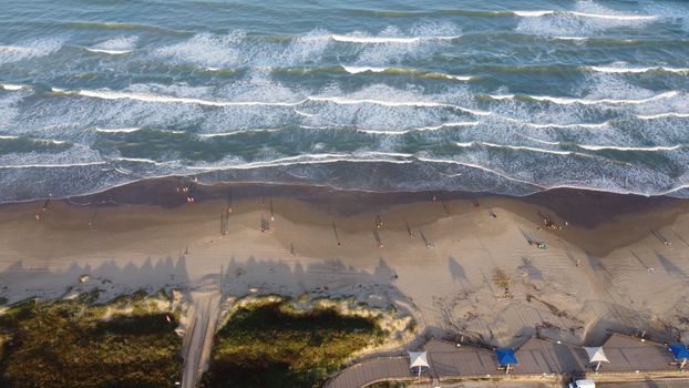 Drone shot capturing a stunning beach scene with crashing ocean waves.