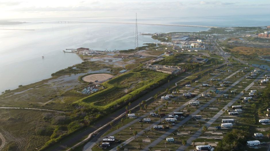 Breathtaking aerial view of a coastal campsite with RVs by the sea through the day.