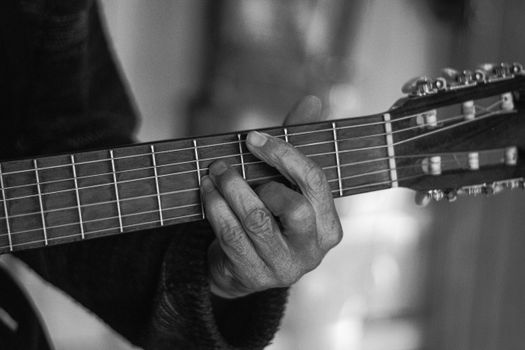 Black and white photo of a musician's hand playing an acoustic guitar, shot in São Paulo, Brazil.. pexels, black, white