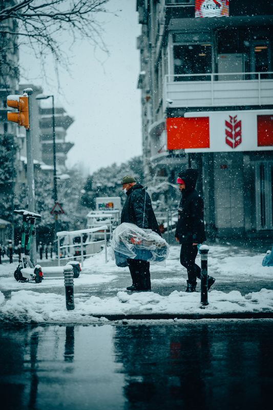 Şehirde karlı bir sokakta yürüyen insanlar