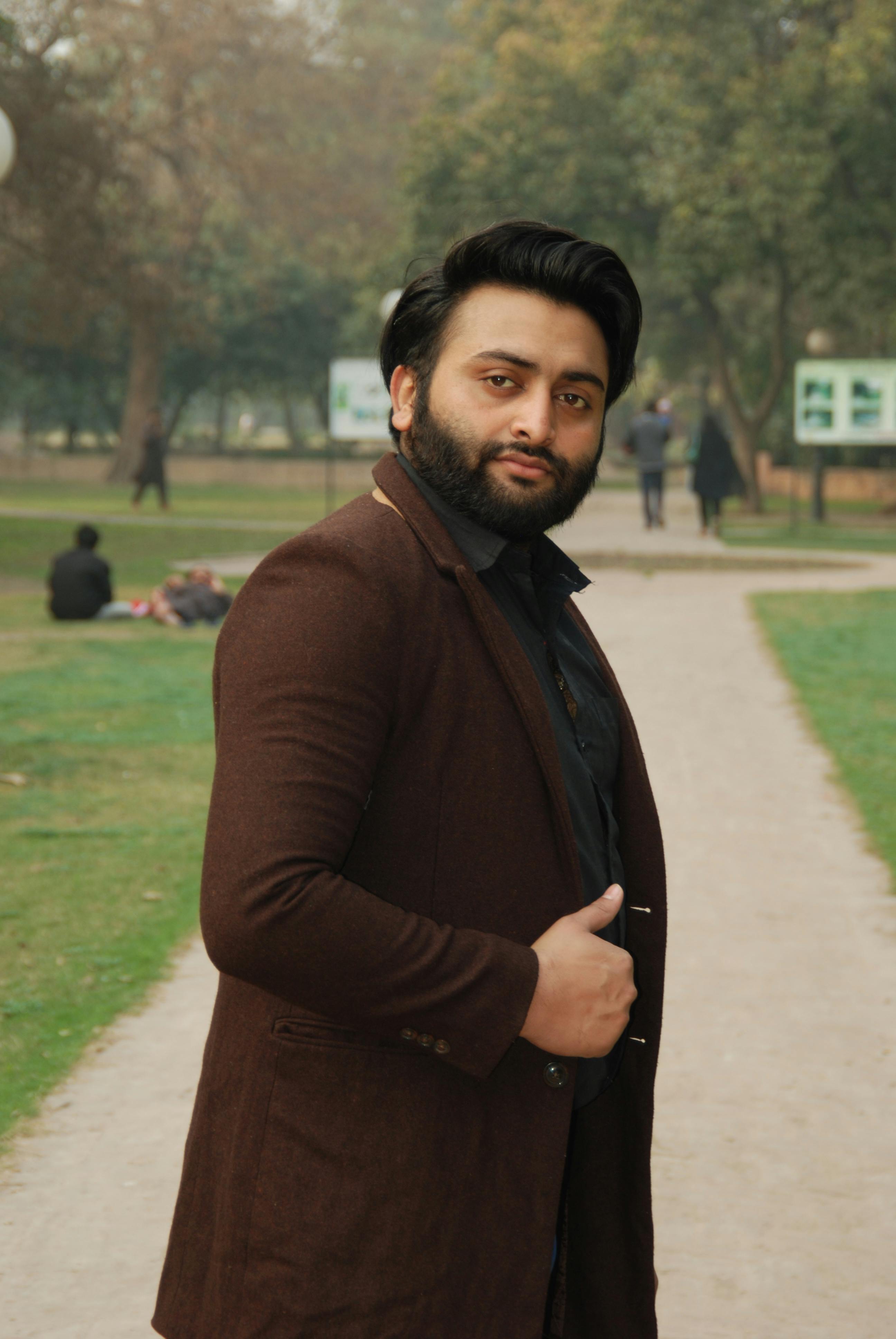 Portrait of a well-dressed man standing in a park in Lahore, Pakistan, showcasing urban style.
