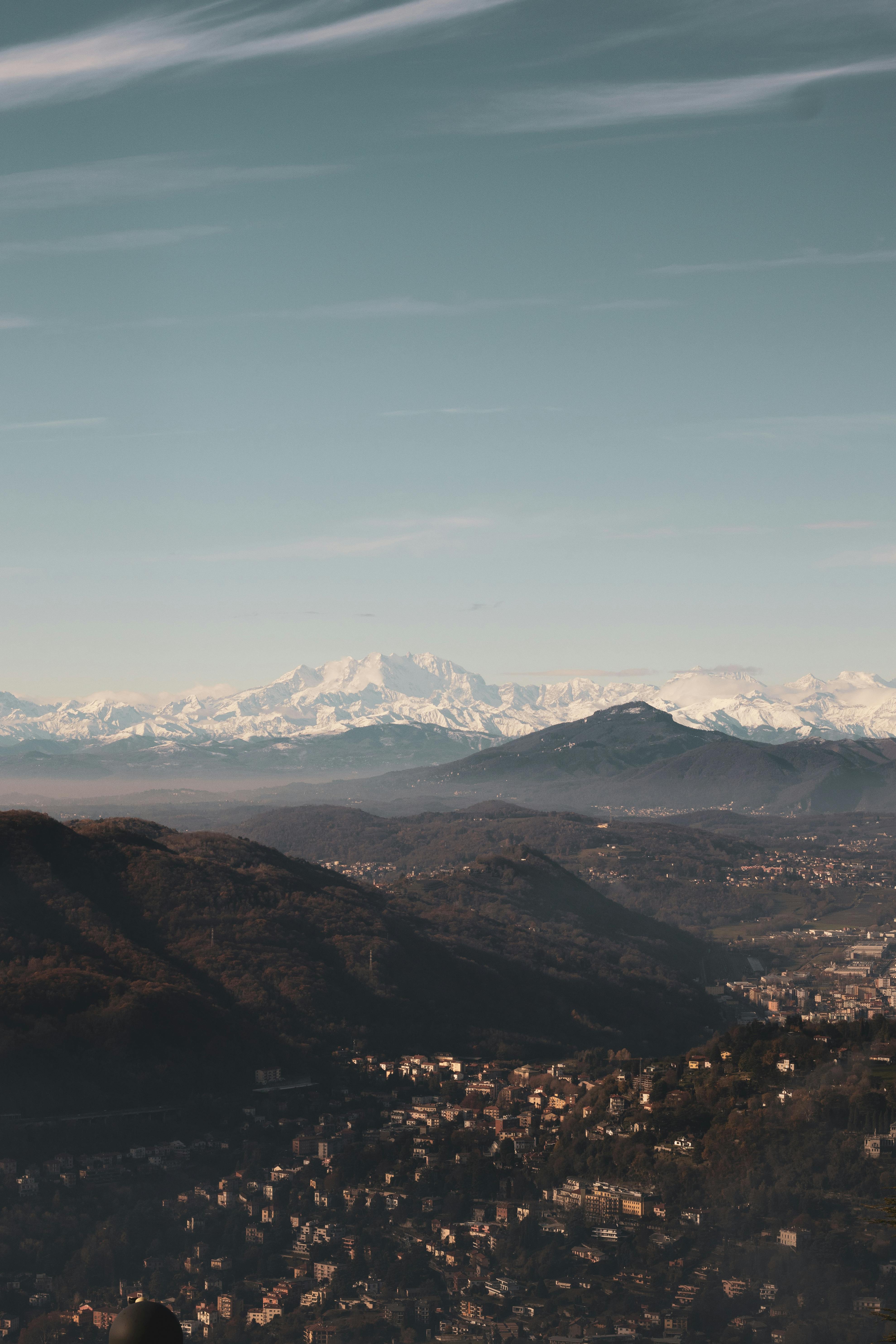 A breathtaking aerial view of a mountainous landscape with snow-capped peaks under a clear blue sky.
