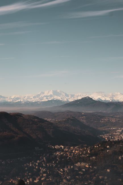 A breathtaking aerial view of a mountainous landscape with snow-capped peaks under a clear blue sky.