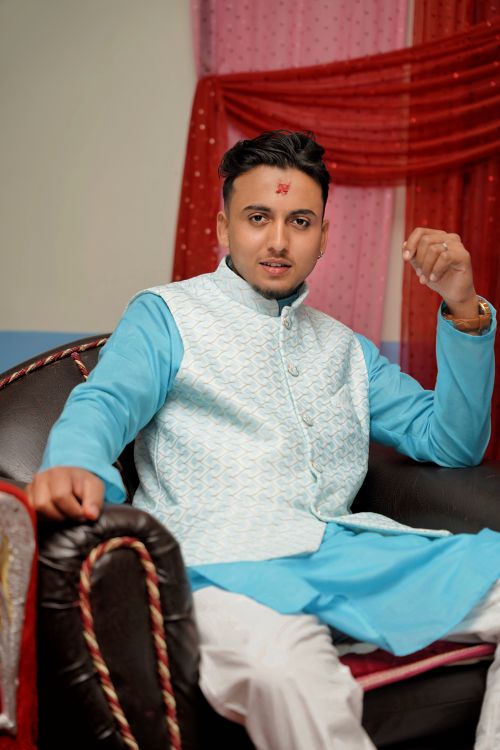 Free Young man in traditional Indian attire sitting on a chair indoors, exuding confidence and style. Stock Photo