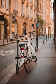 A white bicycle locked on a quaint street in the historic center of Toulouse, France.