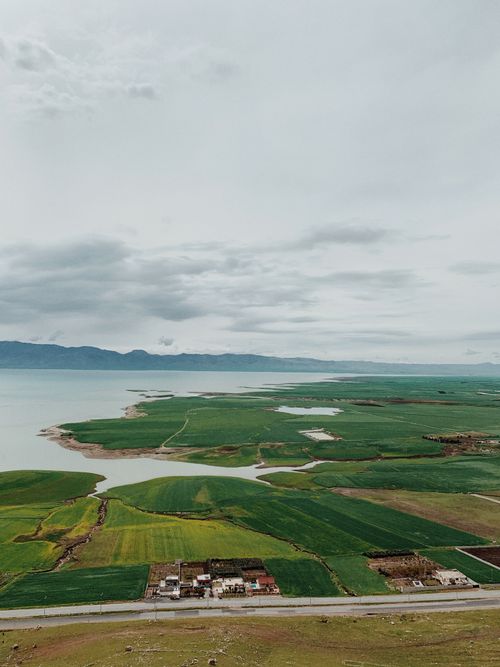 Free Stunning aerial view of vast green fields meeting the lake in Qurago, Iraq. Stock Photo