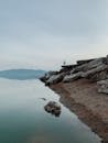 Man Standing on the Rock on the Lakeshore