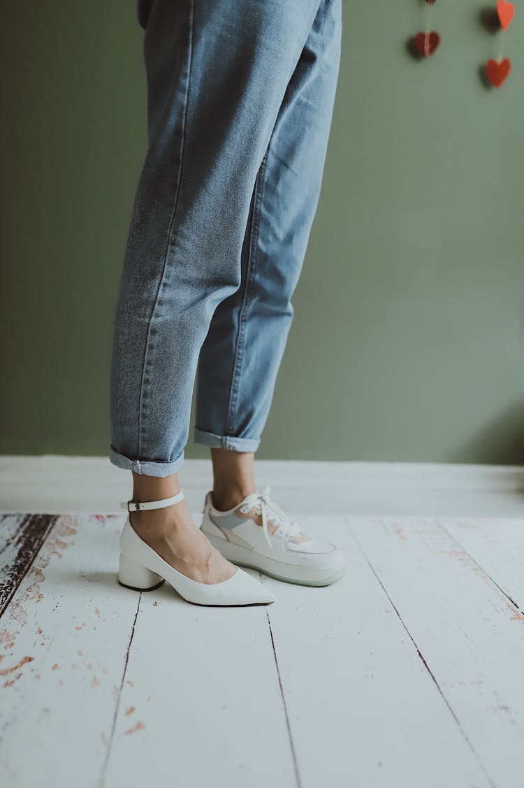 Legs Of A Woman In Light Wash Jeans Wearing Two Different Shoes