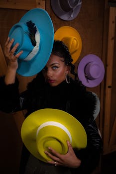 Stylish woman with bright hats in a moody indoor setting.