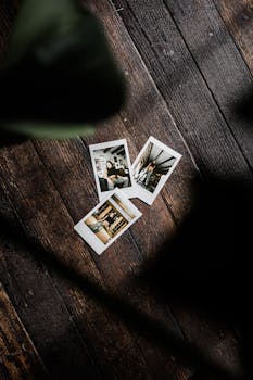Overhead view of vintage Polaroid photos on a rustic wooden floor, artistic and nostalgic scene.