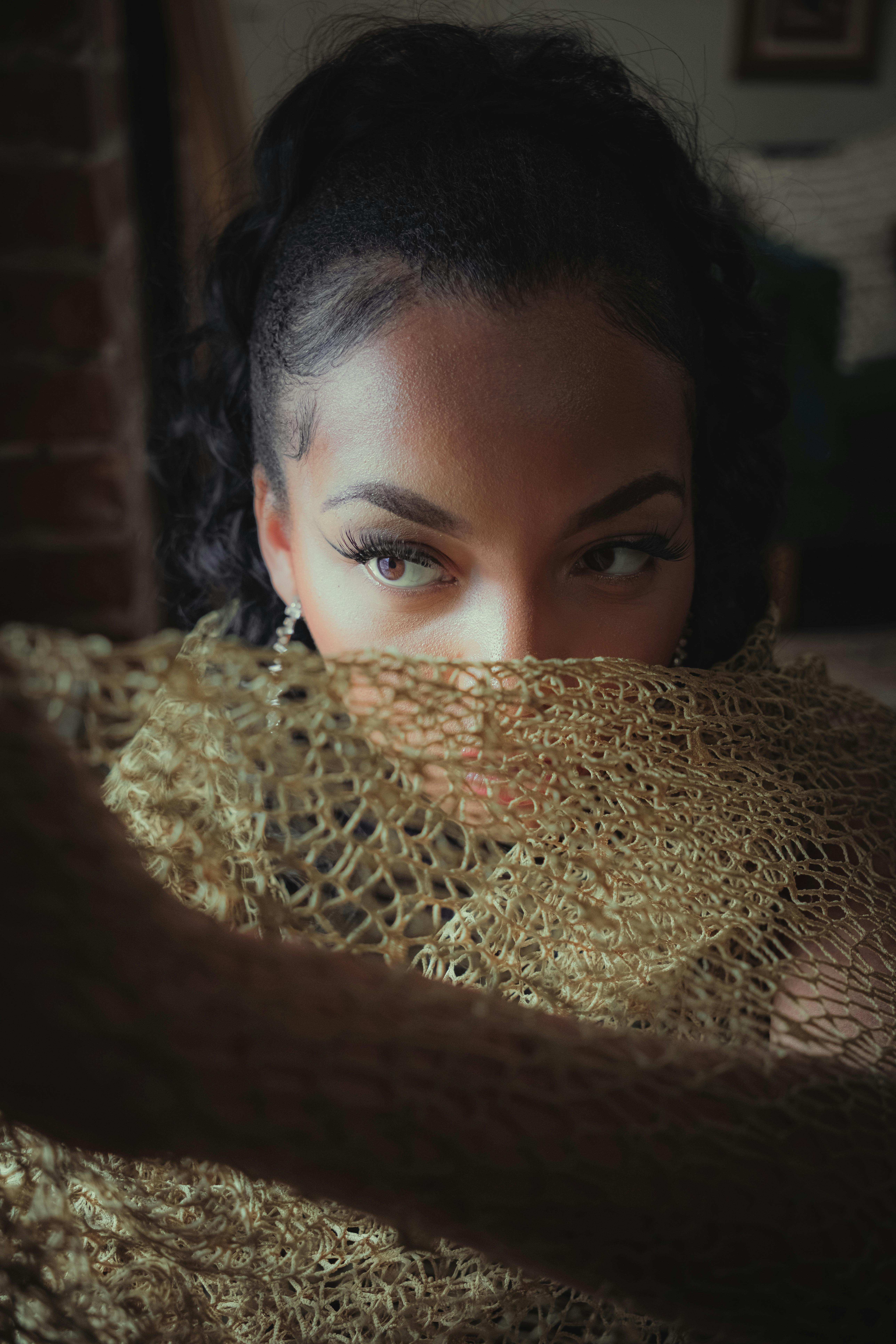 a woman with a gold scarf covering her face