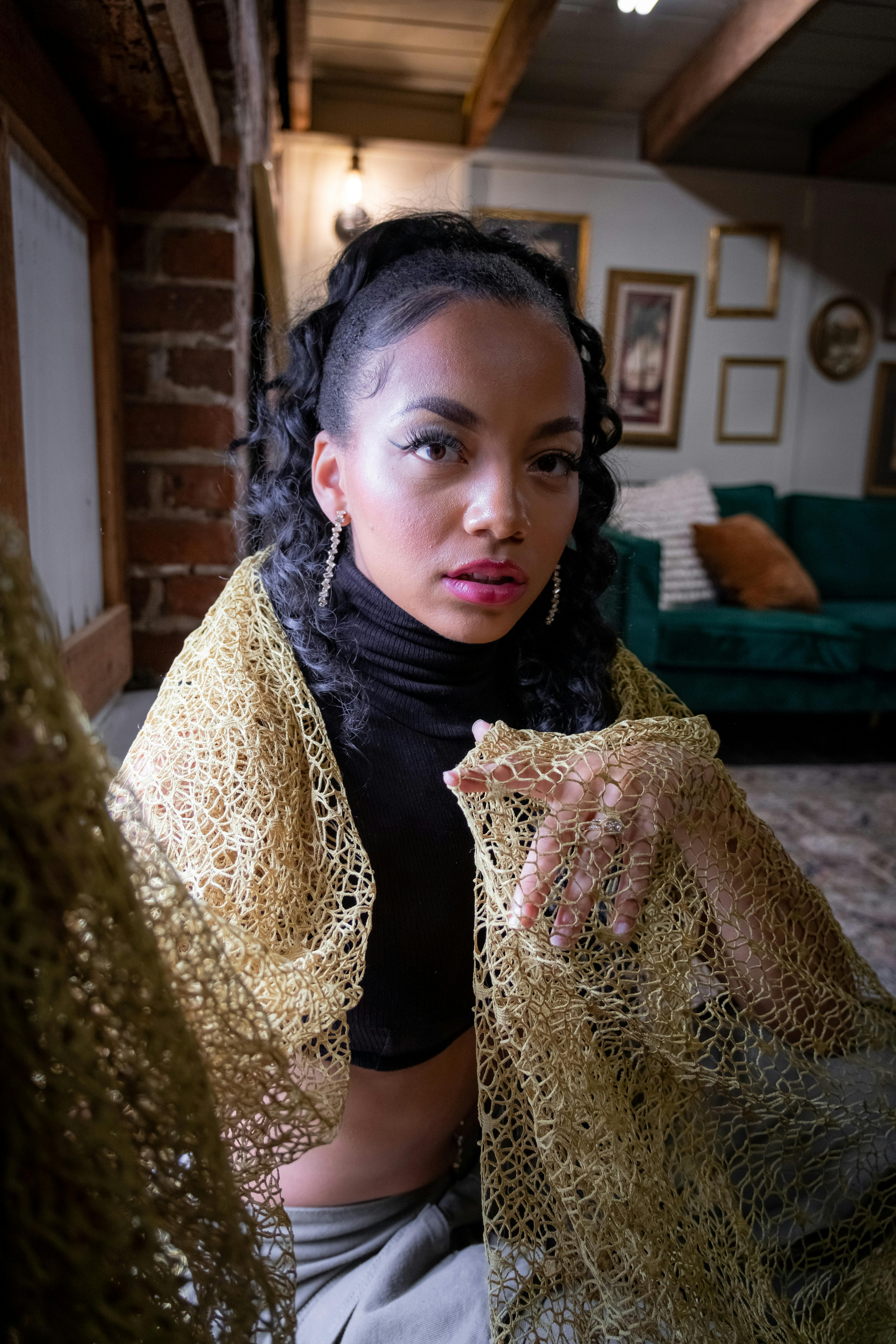 a woman in a black top and gold scarf