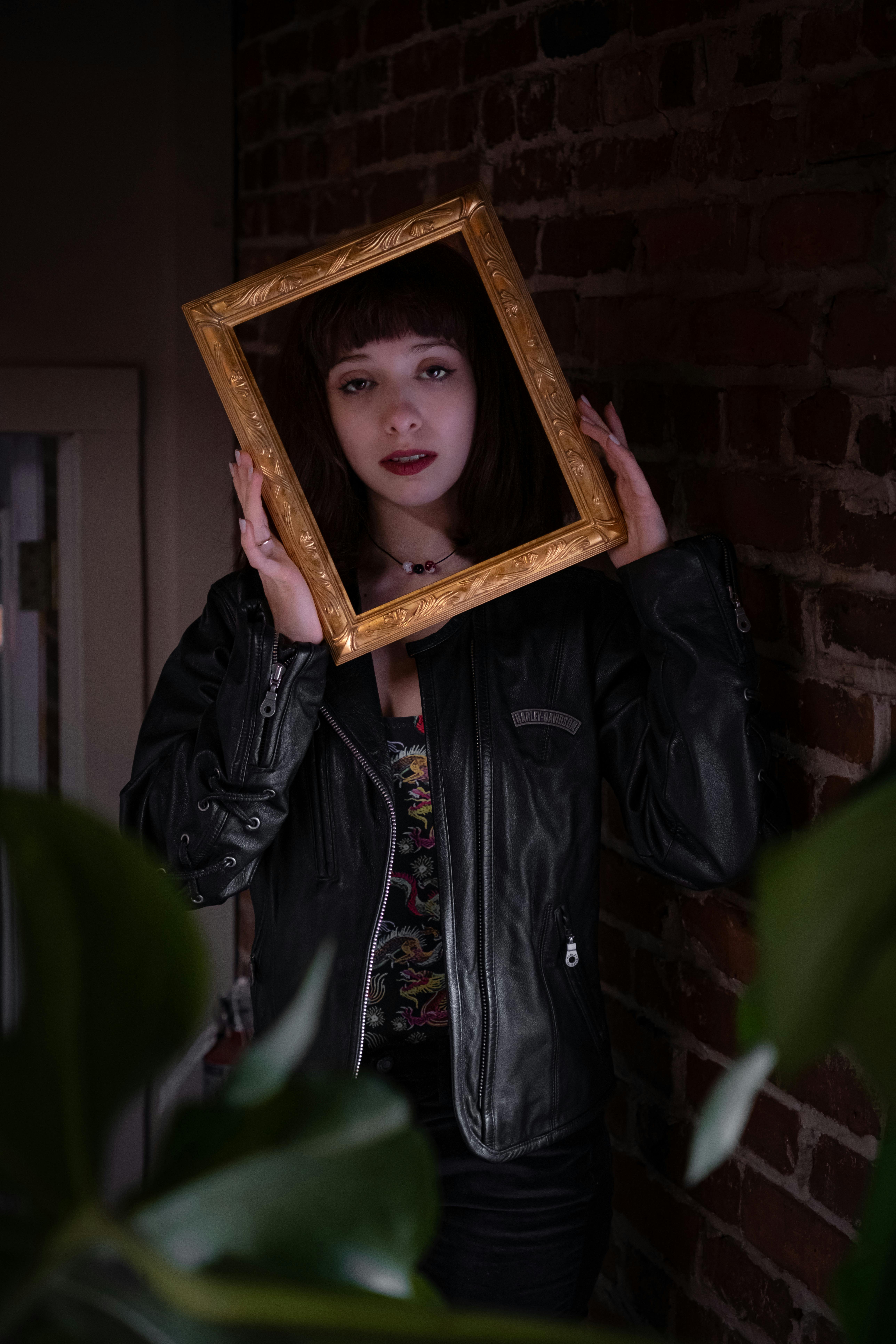 a woman holding a picture frame in front of a brick wall