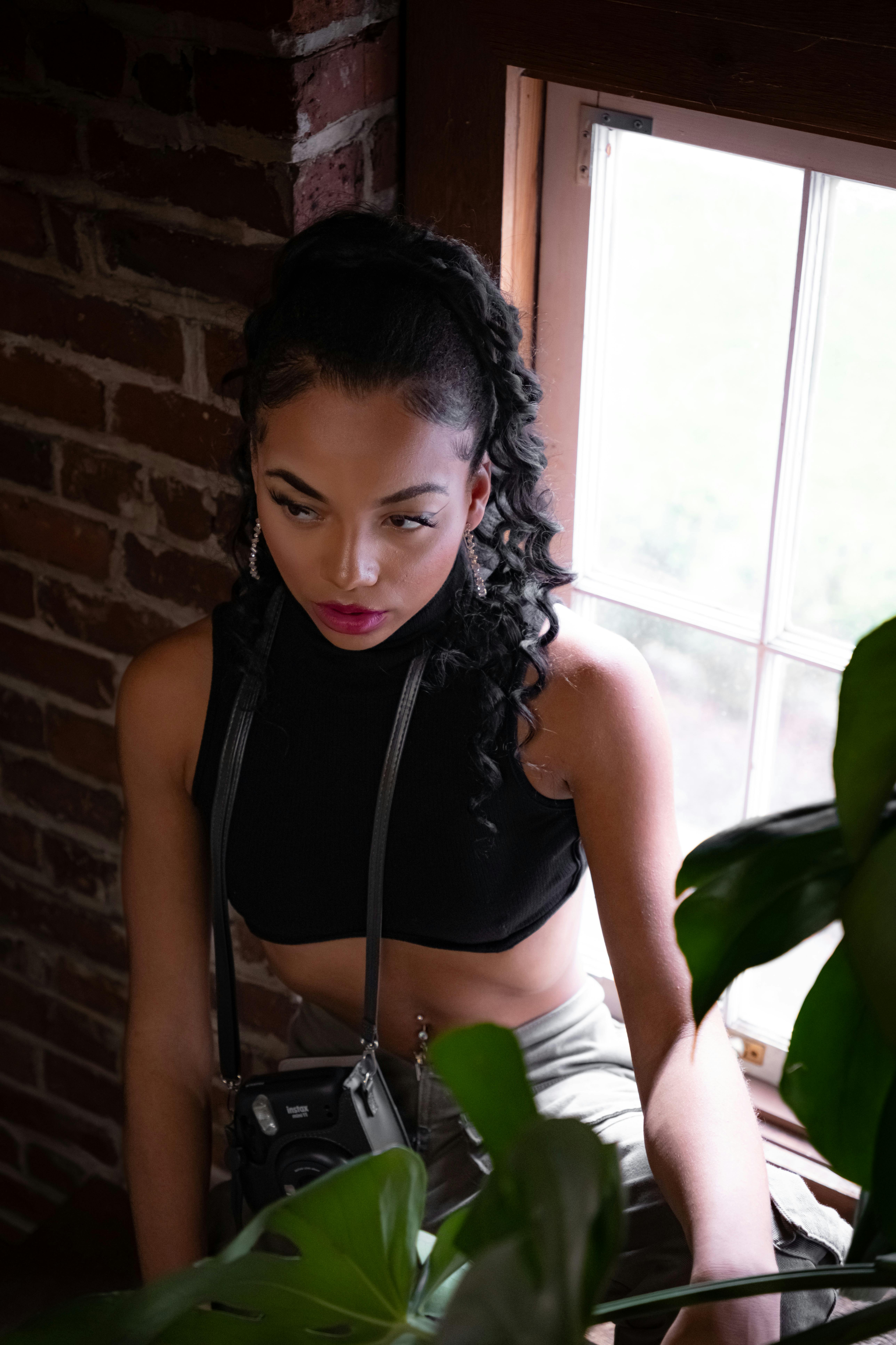 a woman in a crop top and black pants sitting on a window sill