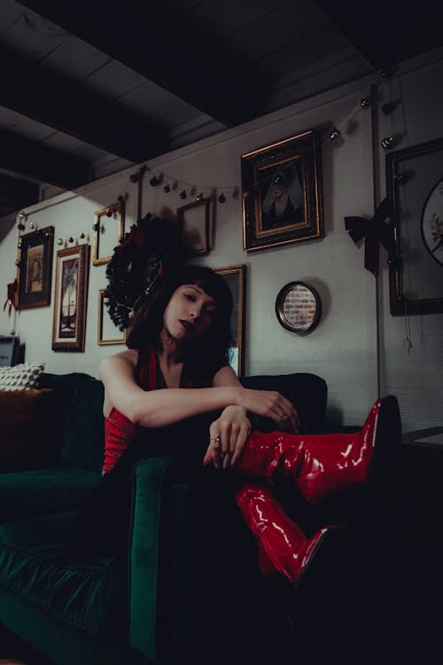 Photo of a Young Woman in Red Boots Sitting on a Sofa 