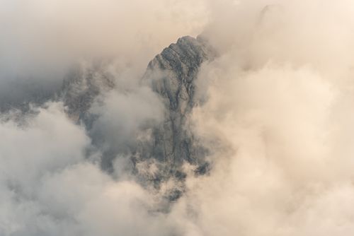Free A rocky mountain peak enveloped in thick clouds, creating a mystical and serene atmosphere. Stock Photo