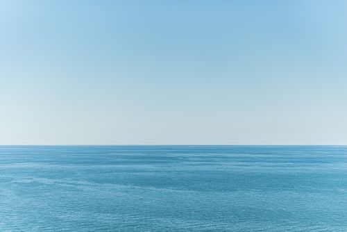 Free Calm ocean waters meet the clear blue sky, creating a tranquil seascape perfect for relaxation themes. Stock Photo