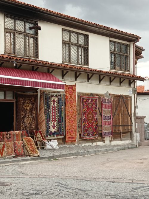 Free Traditional oriental rugs displayed outside a charming urban shop, showcasing vibrant colors and craftsmanship. Stock Photo
