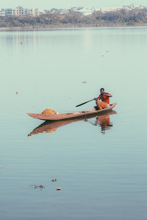 A Man Paddling a Wooden Boat