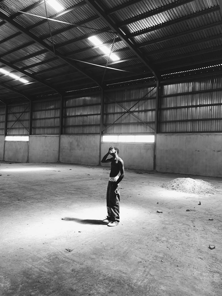 Black And White Picture Of A Man Standing In An Empty Warehouse 