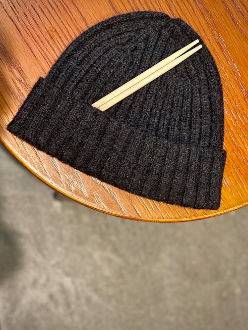 Black Knit Hat with Chopsticks on Wooden Suface