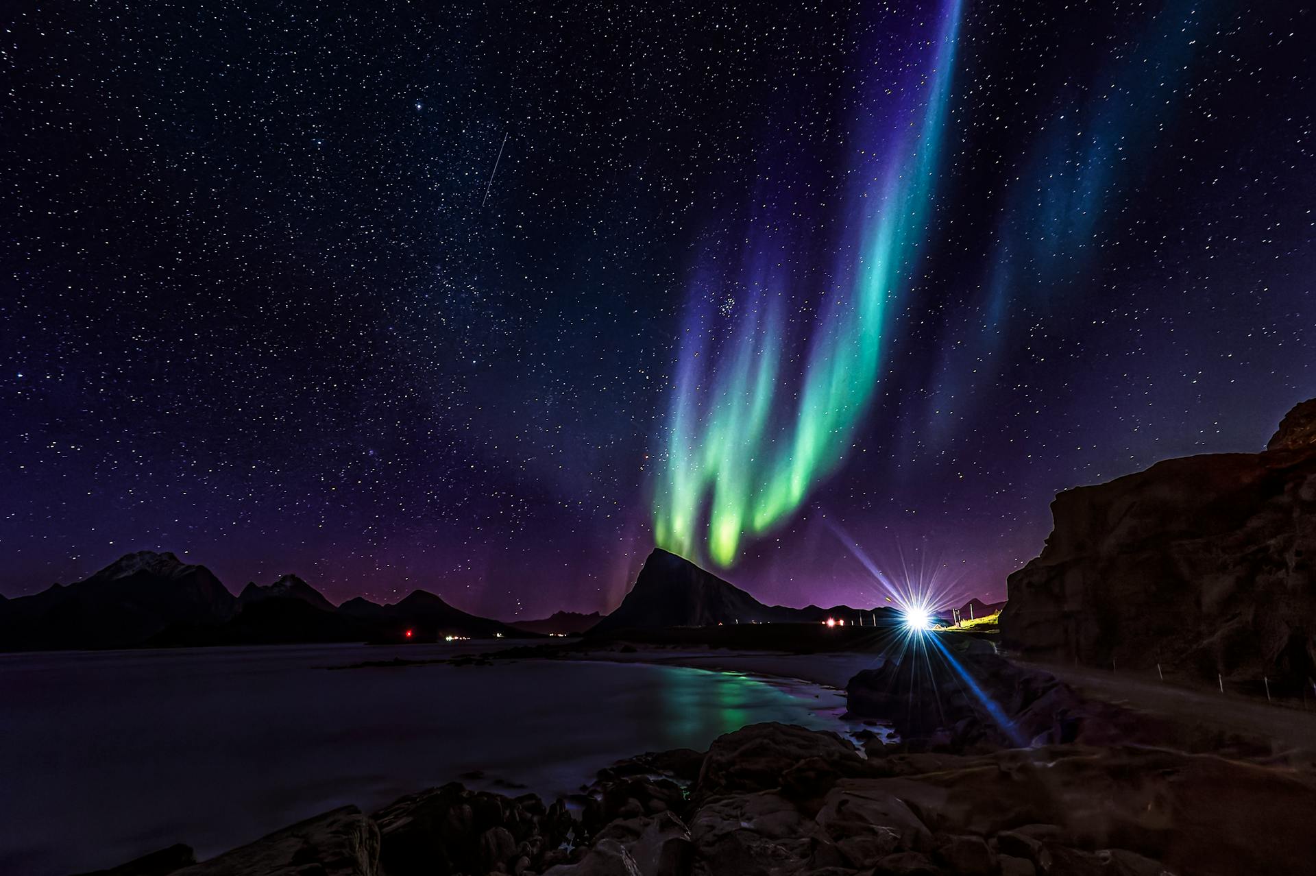 Capture the ethereal beauty of the Northern Lights illuminating the Lofoten Islands' landscape at night.