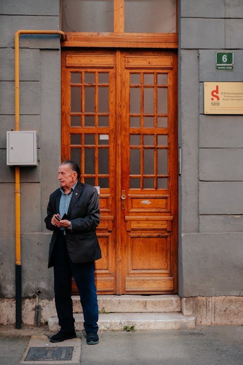 Old Man Standing near Building Wooden Doors